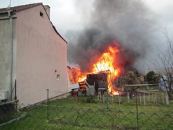 Požár dřevěné chaty na hranici pozemků. Plameny poškodily sousední rodinný dům. 