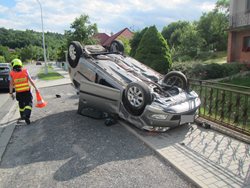 Dopravní nehoda dvou osobních vozidel ve Zlíně. Jedno z vozidel zůstalo po srážce mimo komunikaci na střeše.