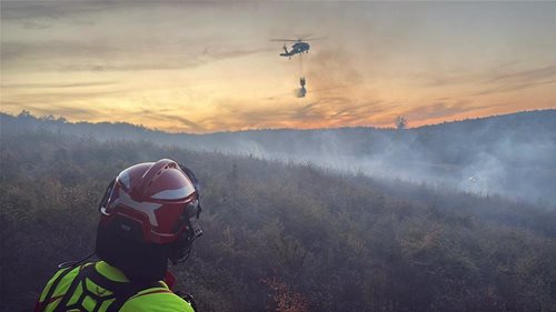 Lesní požár zasáhl přibližně 130 hektarů. Hasičům v těžkém terénu pomáhá Black Hawk