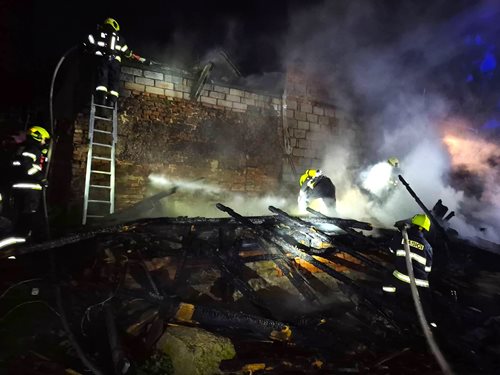Noční požár kůlny ohrozil sousední stavby, jeden hasič zraněn