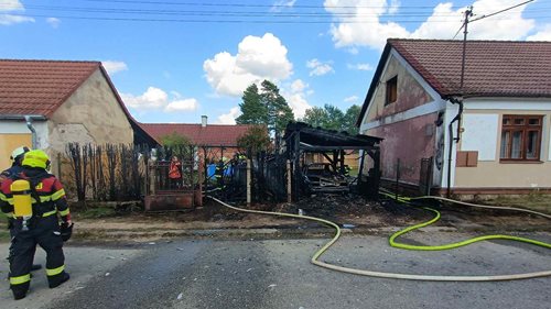 Požár auta a přístřešku se rozšířil na sousední objekt. Hasiči museli rozebrat střechu